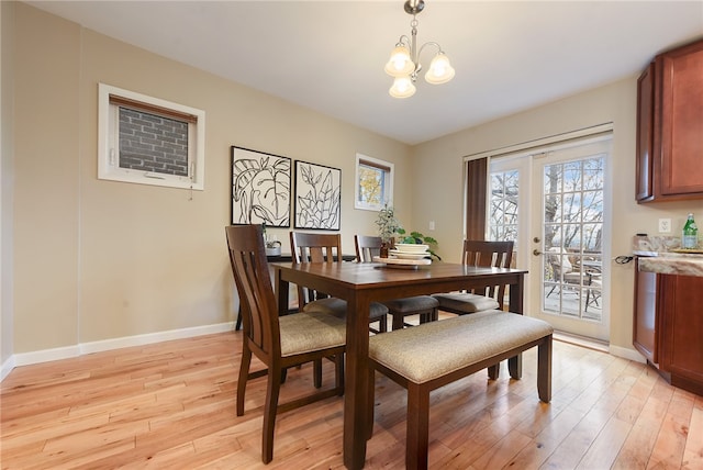 dining space with light hardwood / wood-style flooring and a notable chandelier