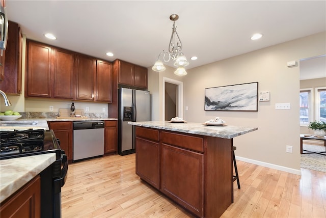 kitchen featuring pendant lighting, stainless steel appliances, a kitchen island, and light hardwood / wood-style flooring