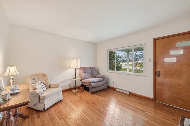 living area with hardwood / wood-style floors and a baseboard heating unit