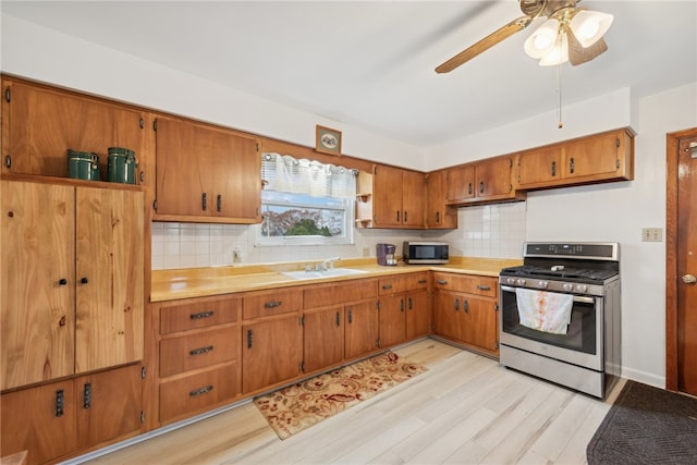 kitchen with appliances with stainless steel finishes, light wood-type flooring, tasteful backsplash, and sink