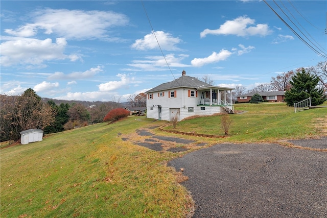 exterior space with covered porch, a garage, a storage shed, and a front yard