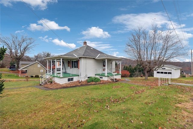 view of front of property featuring a front yard, a garage, an outdoor structure, and covered porch