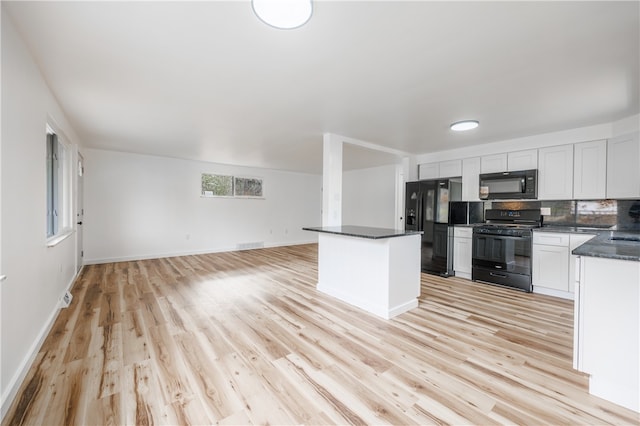 kitchen featuring light wood-type flooring, backsplash, black appliances, white cabinets, and a center island