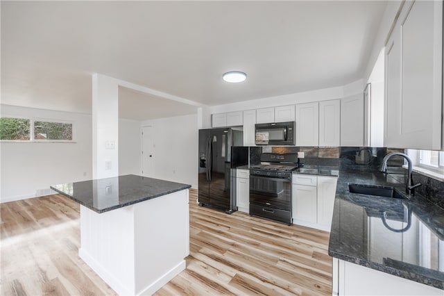 kitchen with white cabinets, sink, dark stone countertops, and black appliances