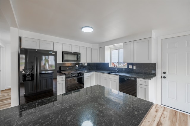 kitchen featuring hardwood / wood-style floors, sink, white cabinetry, and black appliances