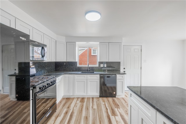 kitchen featuring light wood-type flooring, backsplash, black appliances, dark stone countertops, and white cabinets