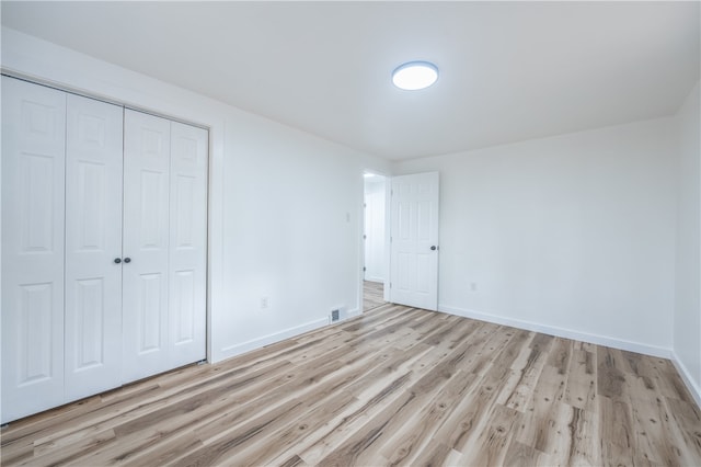 unfurnished bedroom featuring light hardwood / wood-style floors and a closet