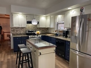 kitchen with blue cabinetry, a center island, stainless steel appliances, and white cabinets