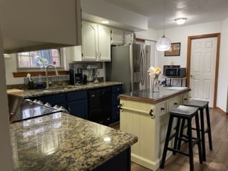 kitchen featuring a kitchen island, dark hardwood / wood-style flooring, stainless steel fridge, decorative light fixtures, and white cabinets