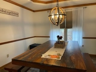 dining space with crown molding and a chandelier