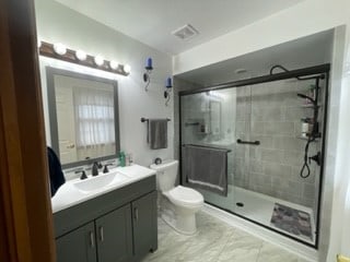 bathroom with vanity, toilet, and a shower with door