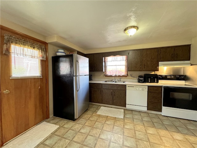 kitchen with white appliances, dark brown cabinetry, and sink