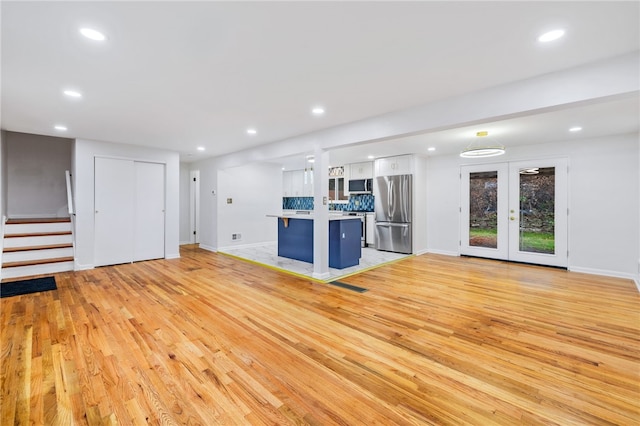 unfurnished living room with french doors and light hardwood / wood-style flooring