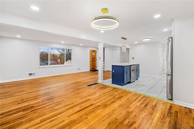 kitchen featuring wine cooler, blue cabinets, light hardwood / wood-style flooring, and hanging light fixtures