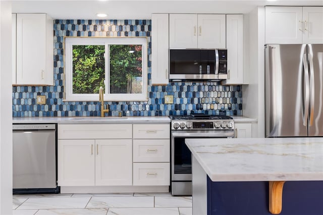 kitchen featuring white cabinetry, sink, light stone countertops, backsplash, and appliances with stainless steel finishes