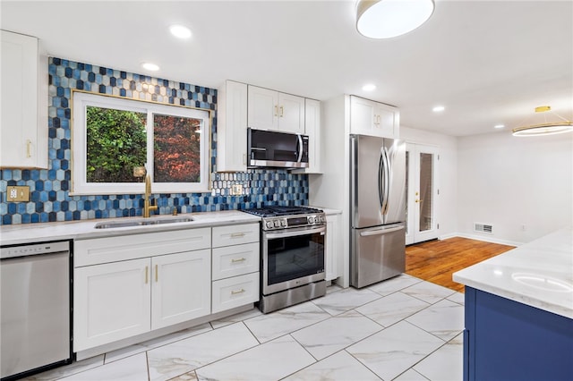 kitchen with white cabinetry, sink, backsplash, light hardwood / wood-style floors, and appliances with stainless steel finishes