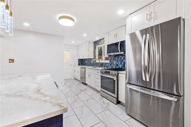 kitchen with backsplash, white cabinets, sink, hanging light fixtures, and stainless steel appliances