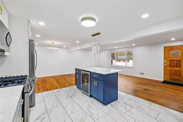 kitchen featuring blue cabinetry, beverage cooler, stainless steel appliances, light hardwood / wood-style flooring, and decorative light fixtures