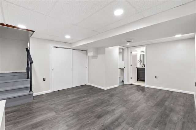 basement with a drop ceiling and dark hardwood / wood-style flooring