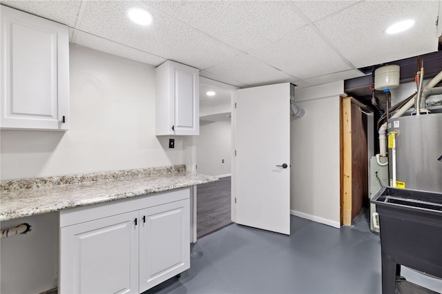 kitchen with white cabinets, a paneled ceiling, and water heater