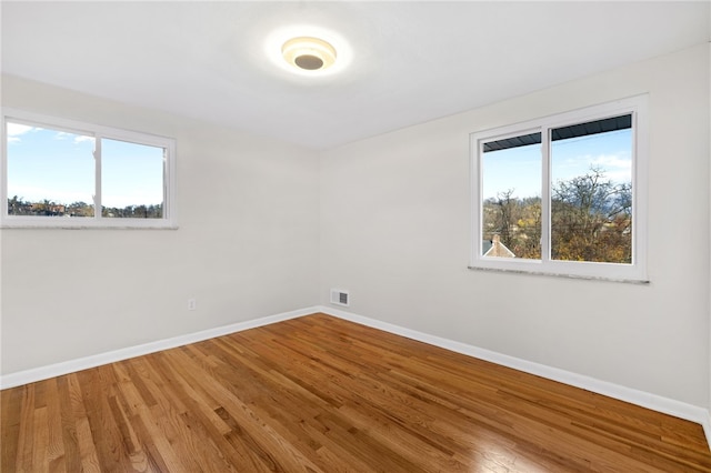 unfurnished room with a wealth of natural light and hardwood / wood-style flooring