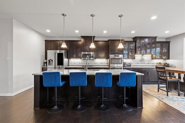 kitchen with hanging light fixtures, a kitchen island with sink, and appliances with stainless steel finishes