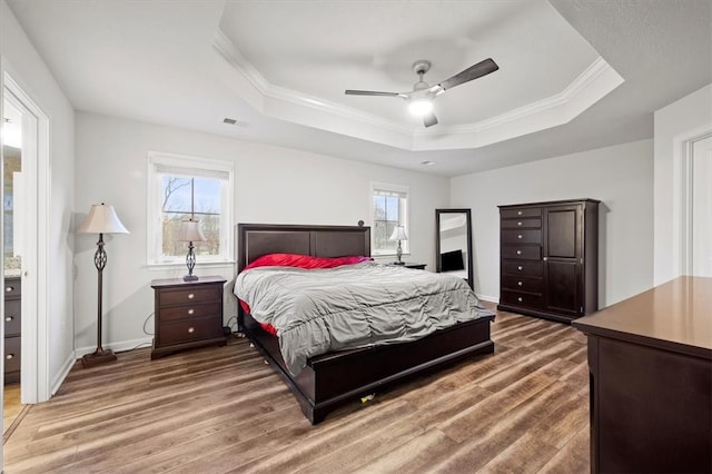 bedroom with a raised ceiling, multiple windows, ceiling fan, and dark wood-type flooring