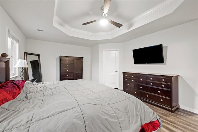 bedroom with hardwood / wood-style floors, a tray ceiling, and ceiling fan