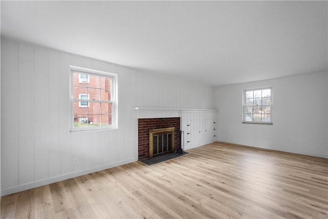 unfurnished living room with a brick fireplace and light hardwood / wood-style flooring