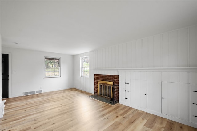 unfurnished living room with light hardwood / wood-style floors and a brick fireplace