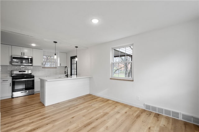 kitchen featuring kitchen peninsula, white cabinetry, light hardwood / wood-style flooring, and stainless steel appliances