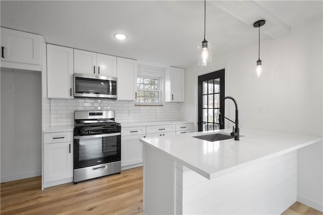 kitchen featuring sink, white cabinets, decorative light fixtures, and appliances with stainless steel finishes