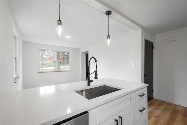 kitchen with pendant lighting, light hardwood / wood-style floors, white cabinetry, and sink