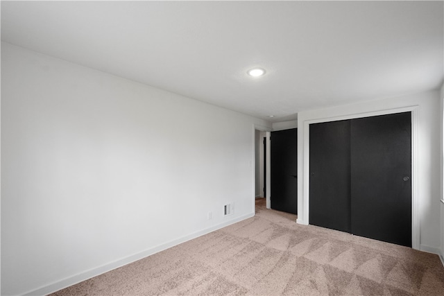 unfurnished bedroom featuring light colored carpet and a closet