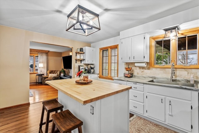 kitchen with white cabinetry, sink, a healthy amount of sunlight, and light wood-type flooring