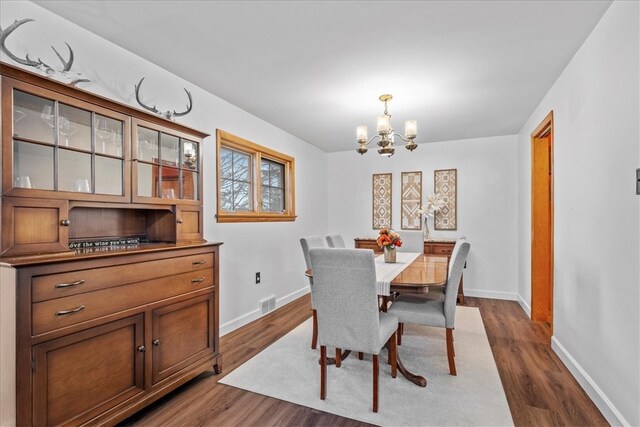 dining space featuring dark wood-type flooring and an inviting chandelier