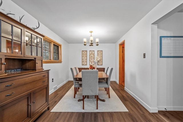 dining space featuring dark hardwood / wood-style flooring and a chandelier