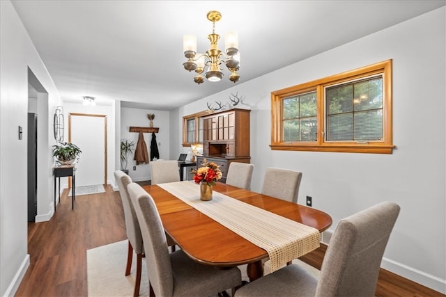 dining room with dark wood-type flooring and a notable chandelier