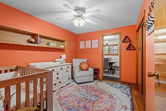 bedroom with a crib, wood-type flooring, and ceiling fan