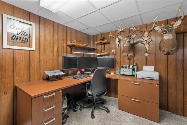 office area featuring a drop ceiling, wood walls, and light colored carpet