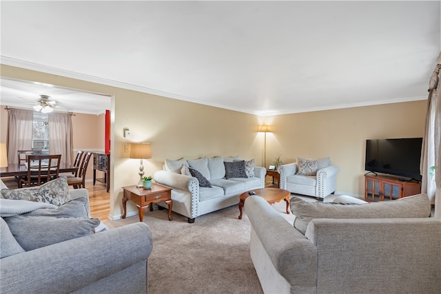 carpeted living room with ceiling fan and ornamental molding