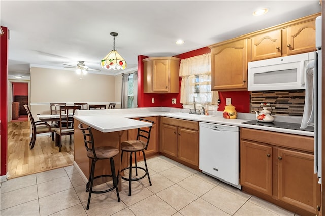 kitchen with white appliances, a kitchen breakfast bar, sink, decorative light fixtures, and kitchen peninsula