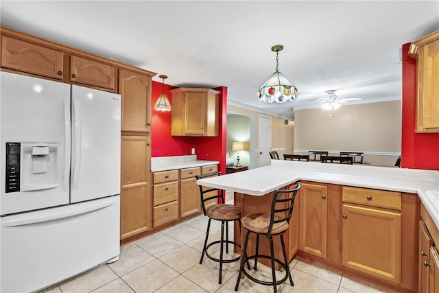 kitchen featuring ceiling fan, white fridge with ice dispenser, pendant lighting, a kitchen bar, and light tile patterned flooring