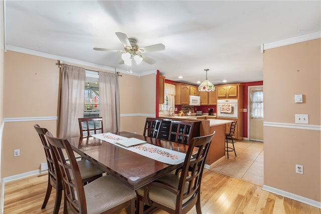 dining room featuring crown molding, sink, ceiling fan, and light wood-type flooring