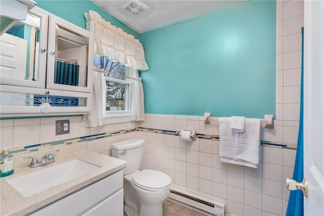 bathroom with vanity, toilet, baseboard heating, and tile walls