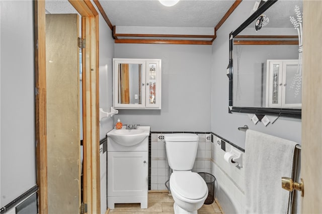 bathroom with vanity, tile patterned floors, toilet, a textured ceiling, and tile walls