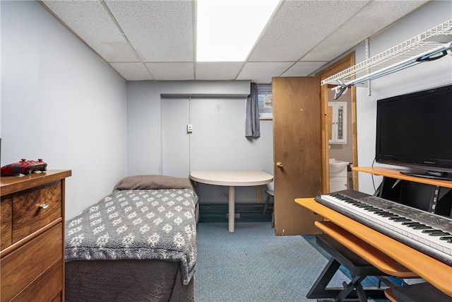 carpeted bedroom featuring a drop ceiling