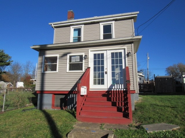 front facade with a front lawn and french doors