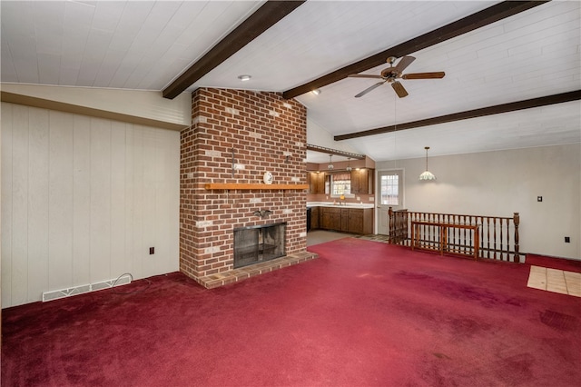 unfurnished living room featuring carpet, lofted ceiling with beams, ceiling fan, and a fireplace