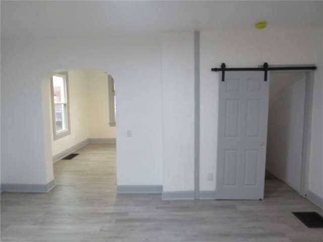 unfurnished room featuring light wood-type flooring and a barn door